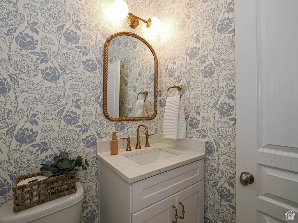 Half bath featuring wallpapered walls and vanity
