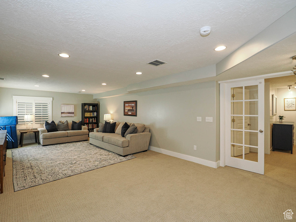 Living room featuring carpet, recessed lighting, a textured ceiling, and french doors