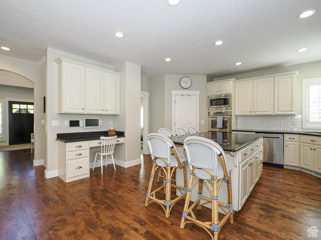Kitchen featuring appliances with stainless steel finishes, arched walkways, a kitchen breakfast bar, plenty of natural light, and recessed lighting