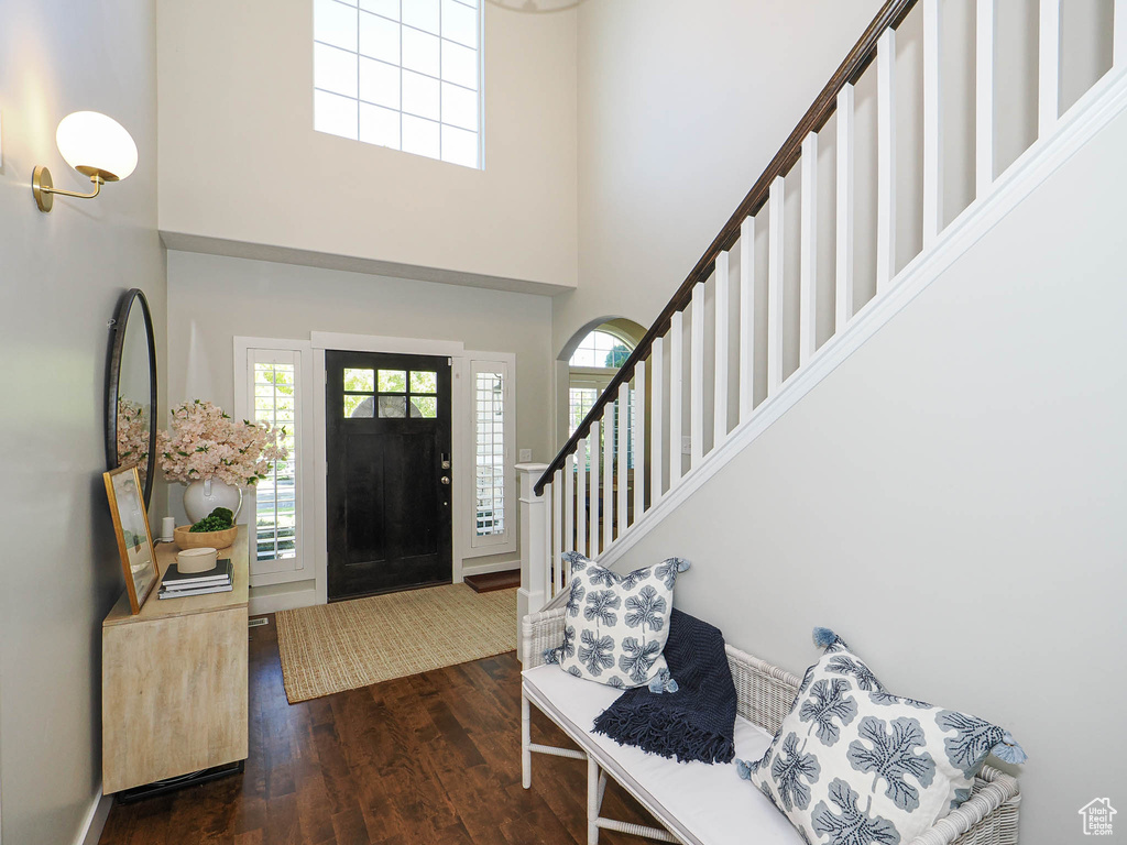 Entrance foyer featuring a towering ceiling, dark wood-style floors, and stairs