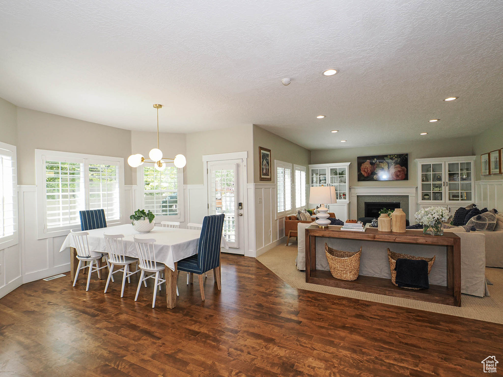 Dining area with a decorative wall, a textured ceiling, wainscoting, recessed lighting, and wood finished floors
