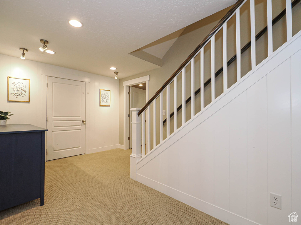 Hallway featuring light colored carpet, stairway, recessed lighting, and a textured ceiling