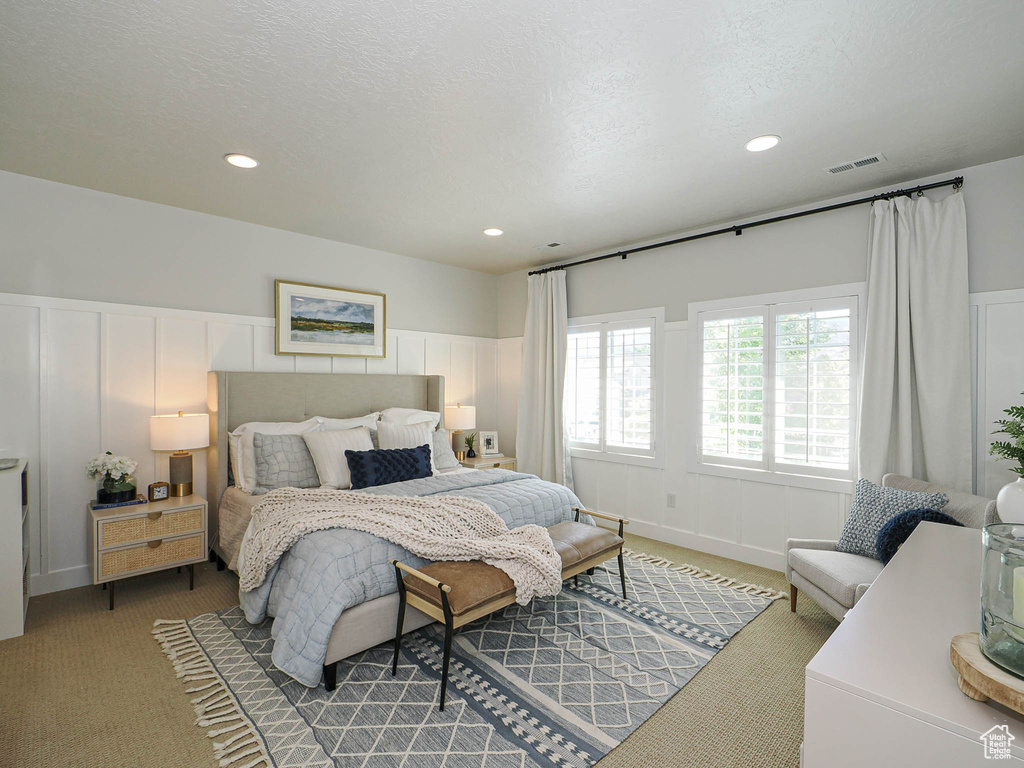 Carpeted bedroom with a decorative wall, a wainscoted wall, and recessed lighting