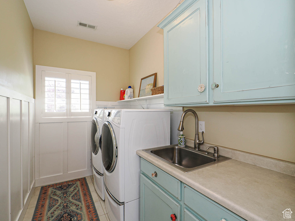 Laundry room featuring cabinet space, washing machine and clothes dryer, light tile patterned floors, and a wainscoted wall