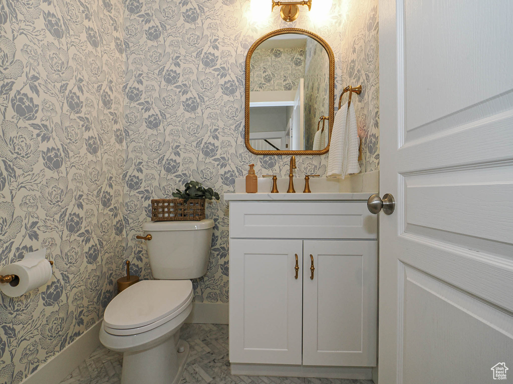 Half bathroom with wallpapered walls and vanity
