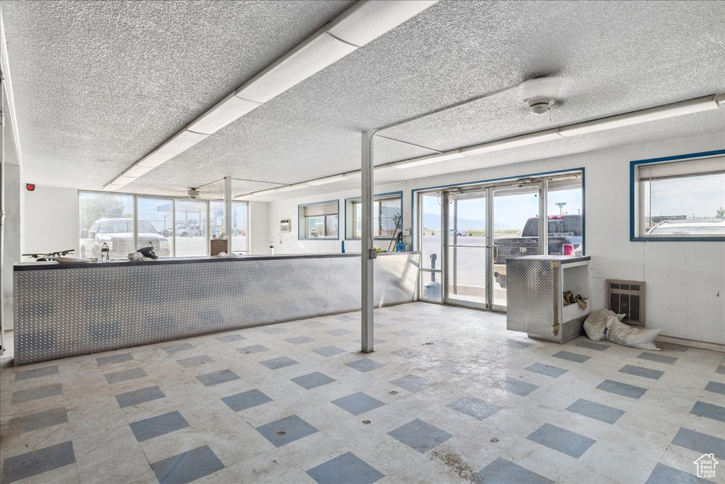 Basement with tile patterned floors, heating unit, and a textured ceiling