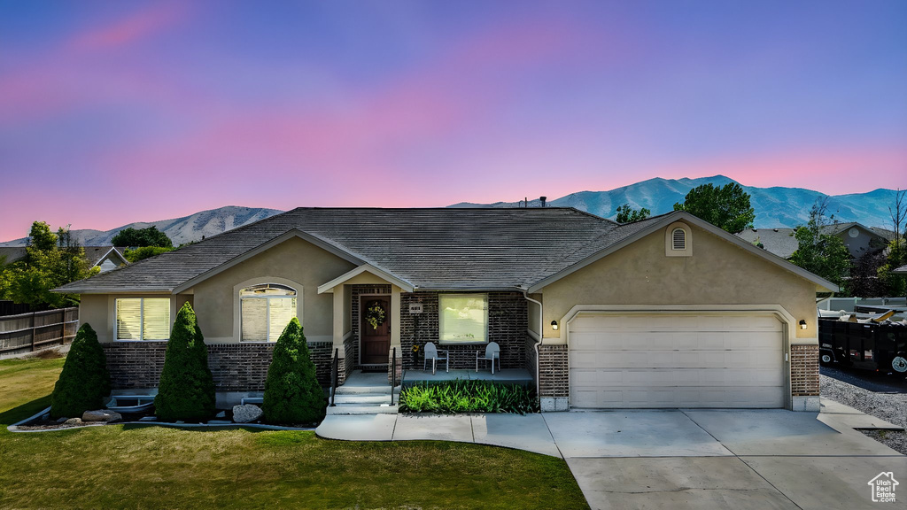 Ranch-style home featuring brick siding, stucco siding, a garage, concrete driveway, and a mountain view