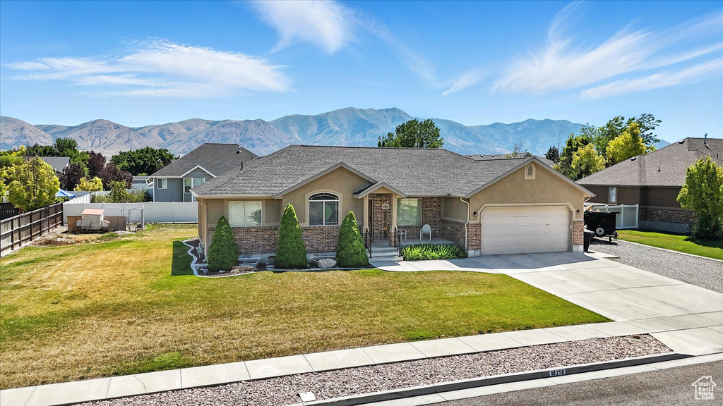 Ranch-style home featuring a garage, brick siding, stucco siding, and a mountain view