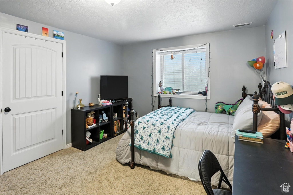 Bedroom with a textured ceiling and carpet floors