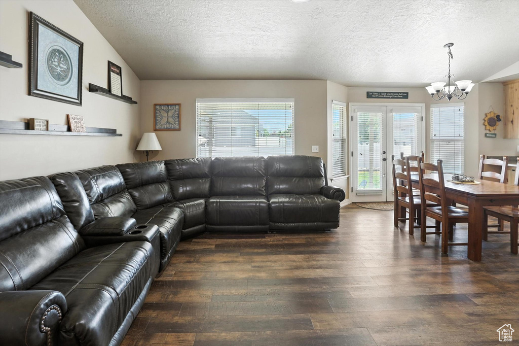 Living room with a chandelier, wood-type flooring, and a textured ceiling