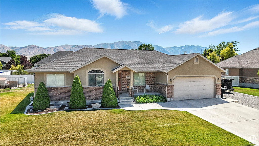 Ranch-style house with stucco siding, a mountain view, brick siding, and an attached garage