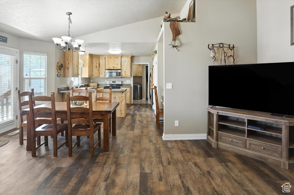 Dining area featuring vaulted ceiling, a chandelier, dark wood finished floors, and a textured ceiling
