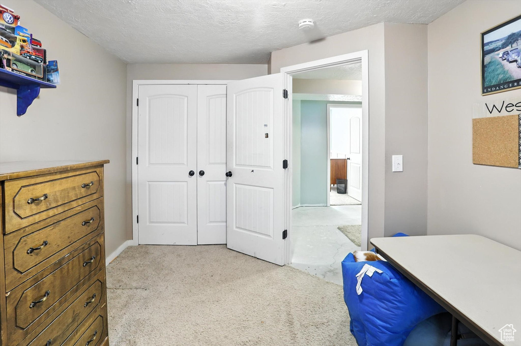 Bedroom with a textured ceiling, light carpet, and a closet