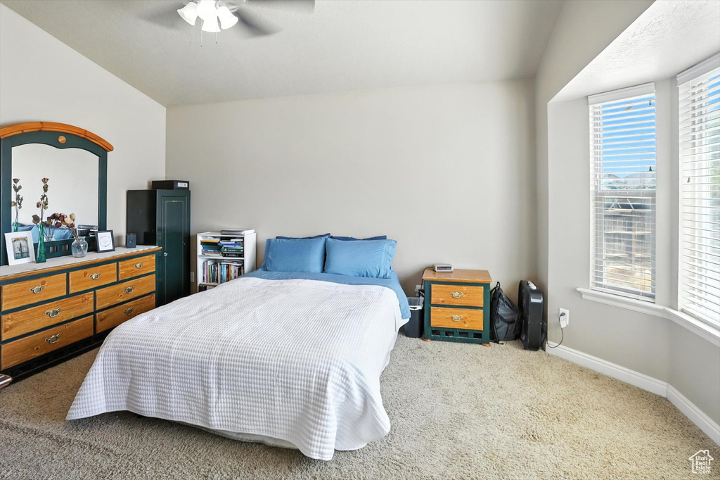 Carpeted bedroom with vaulted ceiling and a ceiling fan