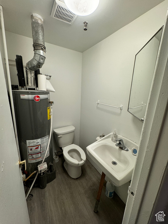 Half bathroom featuring water heater and wood finished floors