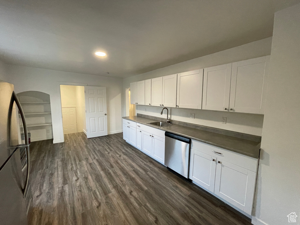 Kitchen featuring appliances with stainless steel finishes, dark countertops, dark wood-type flooring, white cabinetry, and recessed lighting