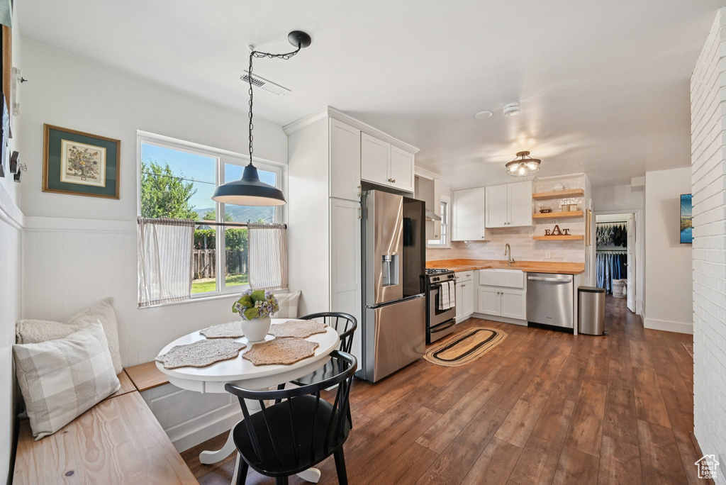 Kitchen featuring stainless steel appliances, wooden counters, white cabinetry, decorative backsplash, and open shelves