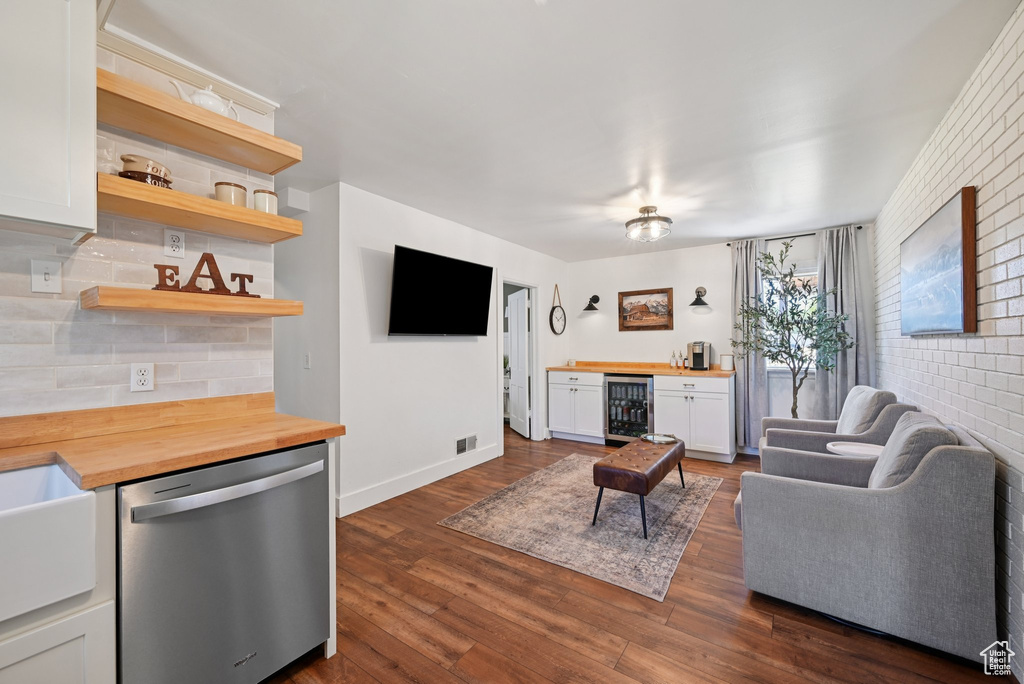 Living area with wine cooler, a bar, and dark wood-style flooring
