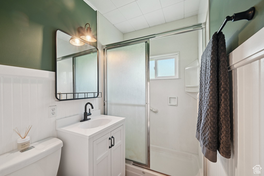 Bathroom featuring vanity, a shower stall, and a wainscoted wall