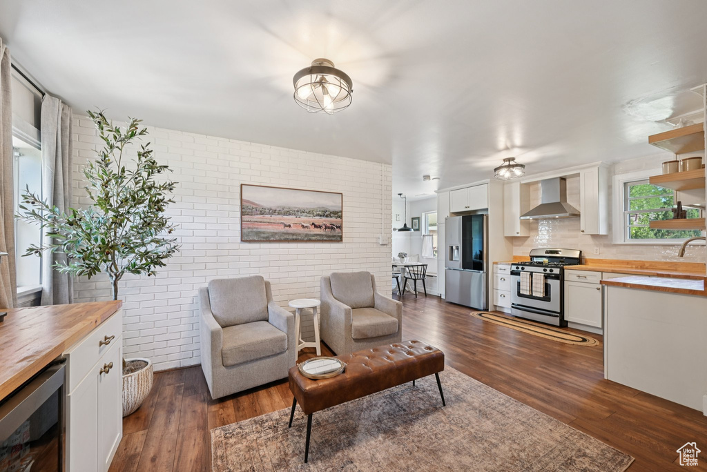 Living room featuring wine cooler, brick wall, and dark wood-type flooring