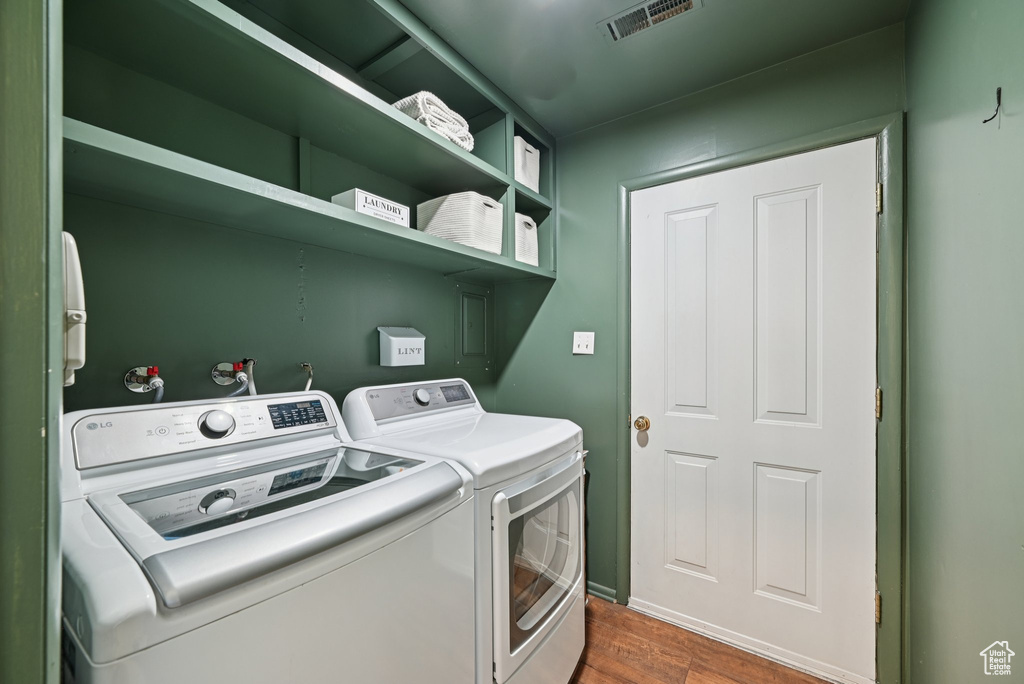 Laundry area with washer and clothes dryer and dark wood-type flooring