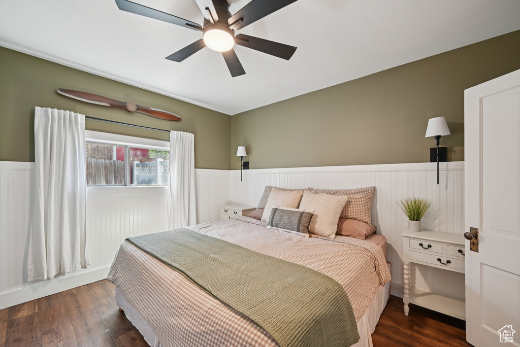 Bedroom featuring a wainscoted wall, dark wood-style floors, and ceiling fan