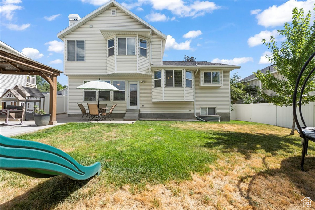 Rear view of house featuring entry steps, a fenced backyard, a chimney, and a patio area