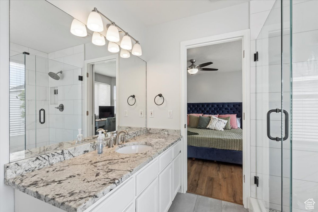 Ensuite bathroom featuring a shower stall, vanity, a ceiling fan, and tile patterned floors