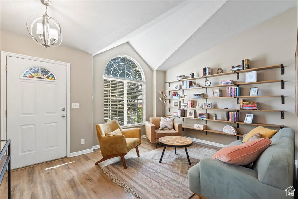 Sitting room with light wood-type flooring, a chandelier, and vaulted ceiling