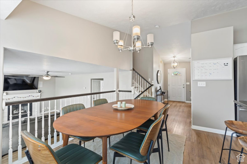 Dining area with stairway, light wood finished floors, a chandelier, and ceiling fan