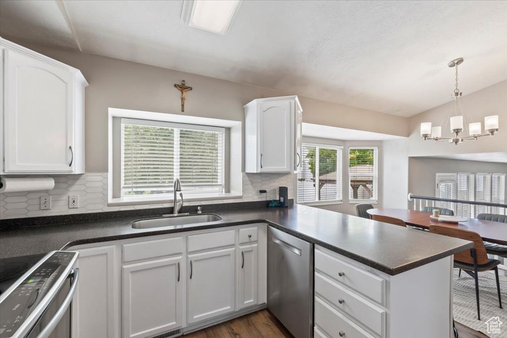 Kitchen featuring appliances with stainless steel finishes, a peninsula, and dark countertops