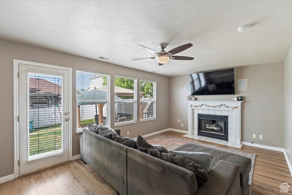 Living room with a ceiling fan, a fireplace, and light wood finished floors