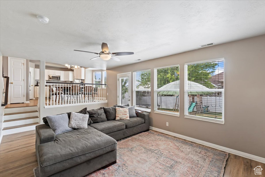Living room with a ceiling fan, light wood-type flooring, and a textured ceiling