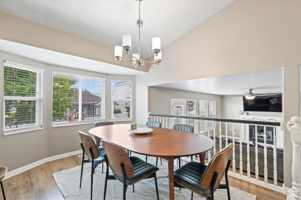Dining room featuring a chandelier, plenty of natural light, light wood-style flooring, and vaulted ceiling