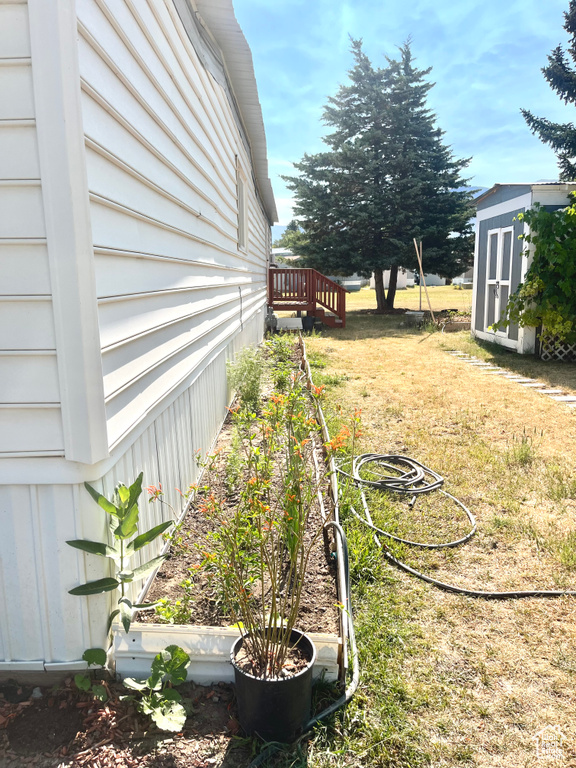 View of yard with a shed, a garden, and a deck