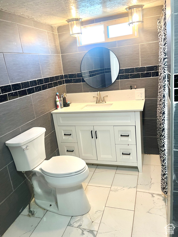 Full bath with tile walls, marble look tiles, and vanity