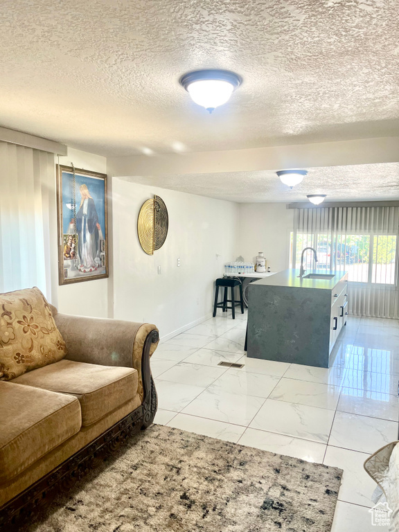 Living area featuring a textured ceiling and light marble finish floors
