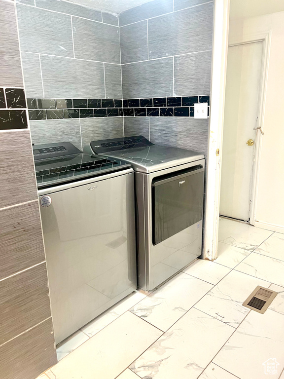 Laundry room with independent washer and dryer and light marble finish floors