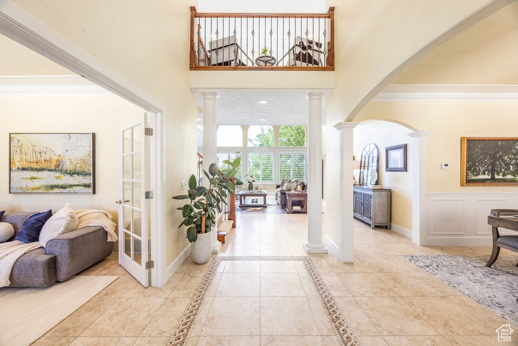 Entrance foyer with decorative columns, arched walkways, and crown molding