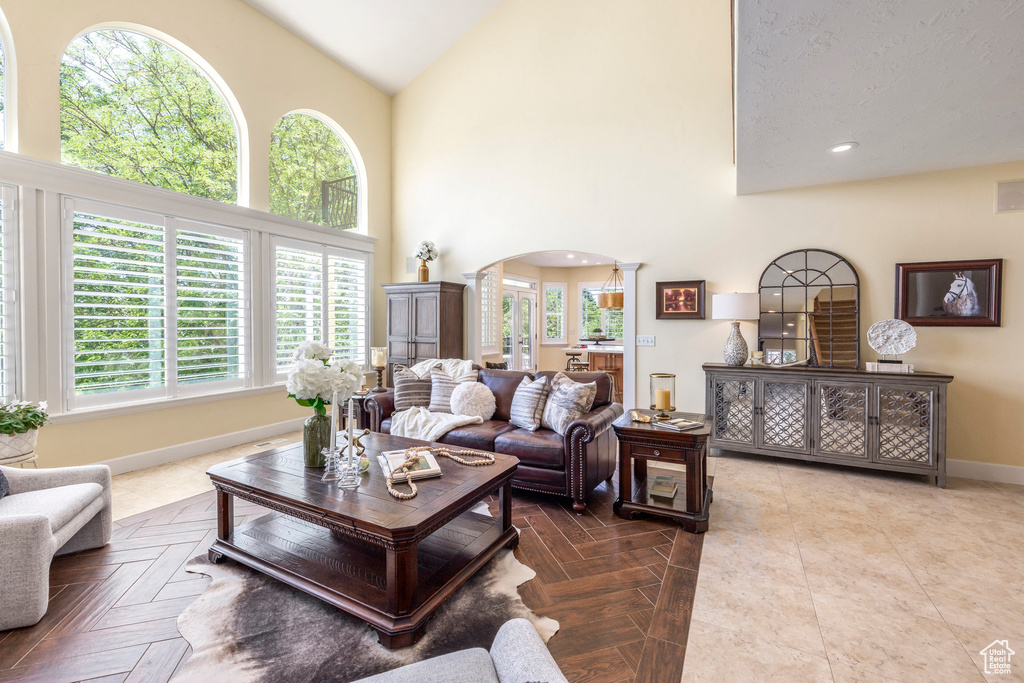 Living area featuring arched walkways, plenty of natural light, high vaulted ceiling, and decorative columns