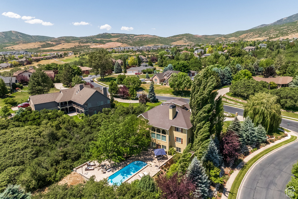 Aerial view of residential area featuring a mountainous background and a pool