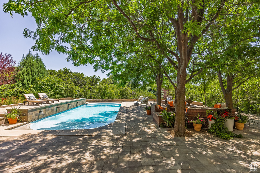 Outdoor pool featuring a patio area, an outdoor hangout area, and view of wooded area