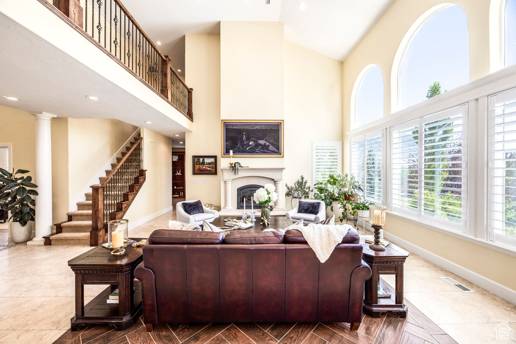 Living room featuring a high ceiling, stairway, a fireplace, decorative columns, and recessed lighting