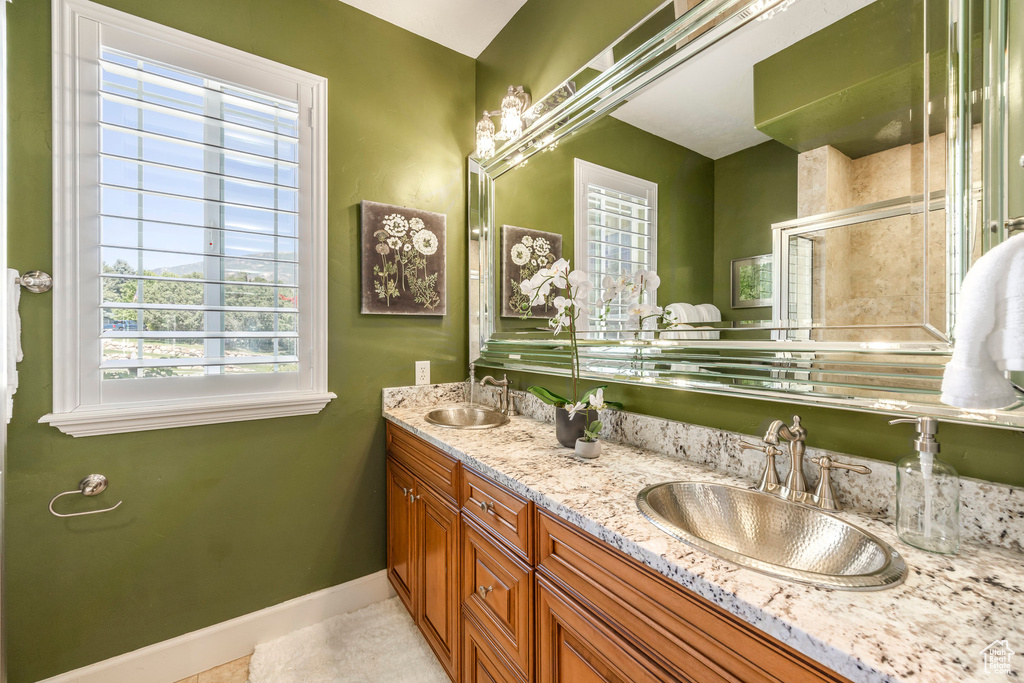 Bathroom featuring double vanity, a shower stall, and tile patterned flooring