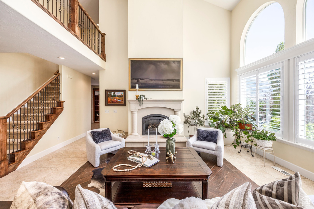 Living area featuring a high ceiling, stairs, and a fireplace with raised hearth