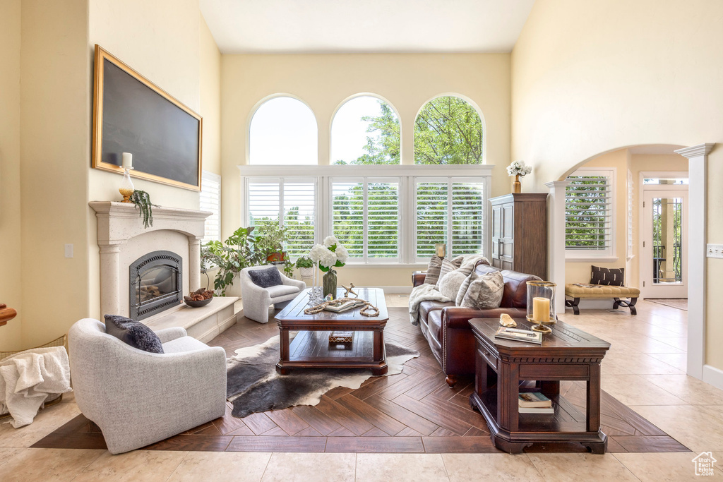 Living area featuring arched walkways, a high ceiling, a glass covered fireplace, and ornate columns