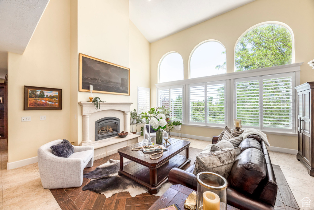 Living room with a glass covered fireplace, high vaulted ceiling, and light tile patterned floors