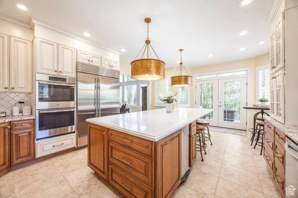 Kitchen featuring appliances with stainless steel finishes, decorative backsplash, french doors, recessed lighting, and a center island
