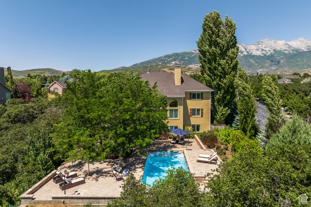Back of property with a patio area, a chimney, and a mountain view