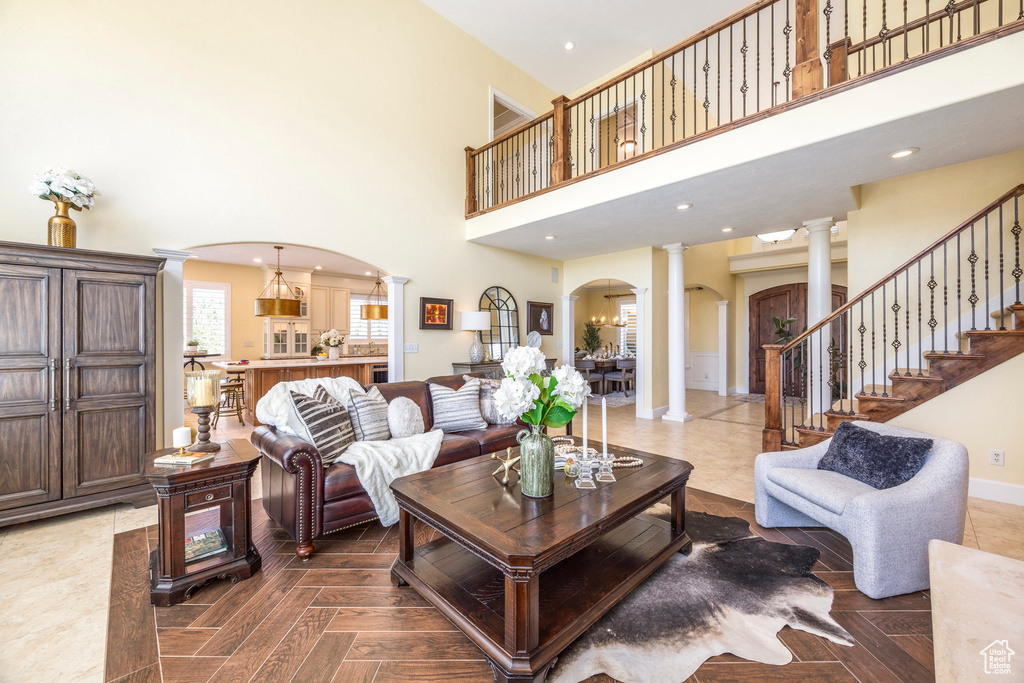 Living room featuring decorative columns, arched walkways, and a towering ceiling